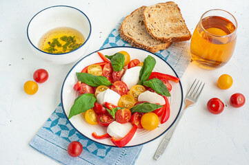 A light summer dinner. Red and yellow vegetable salad, tomato juice, basil sauce and toast.