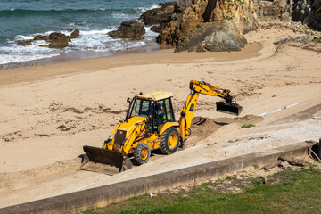 JCB digger rebuilding coastal defences on Tapia de Casariego beach in Asturias Spain