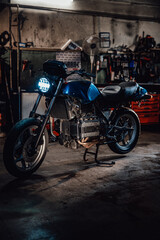 Custom bobber motorcycle with front light on in workshop or garage