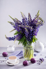Cup of coffee with a bouquet of lupins on white background