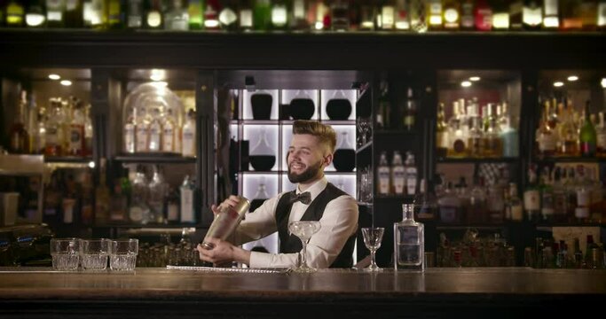 The bartender is mixing a drink in a shaker and smiling. 4k