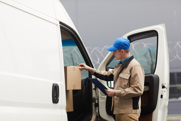 Courier checking the cardboard boxes in the car before shipping
