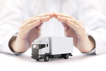 White cargo delivery truck miniature protected by hands - obrazy, fototapety, plakaty