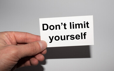 Message on the card DON'T LIMIT YOURSELF, in hands of businessman.