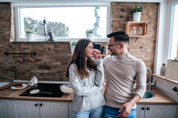 Fototapeta premium Cute couple in the kitchen, standing and looking at each other.