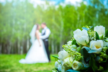 Wedding flowers bouquet with newlywed couple on background