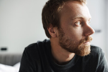 Obraz premium Photo closeup of redhead man looking aside while sitting on bed