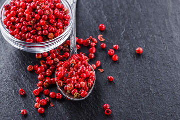 pink peppercorns on a dark stone background