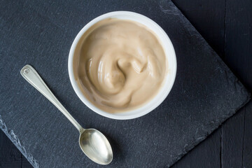 Chocolate flavoured yogurt in cup isolated on black slate background with space for text - overhead photo