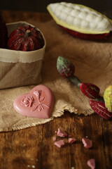 On a wooden table is chocolate, cocoa fruit.
