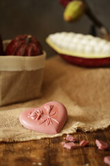 On a wooden table is chocolate, cocoa fruit.
