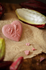 On a wooden table is chocolate, cocoa fruit.

