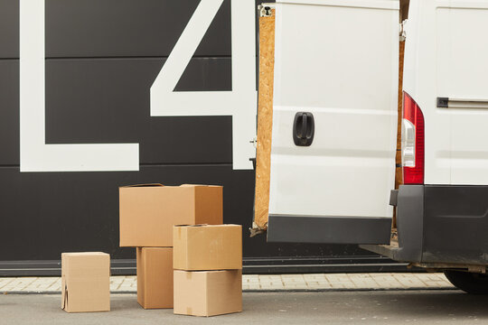 Image of van with opened door and cardboard boxes on the ground This is cargo delivery
