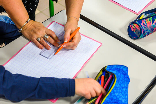 L'institutrice indique les consignes sur le cahier de l'&eacute;l&egrave;ve.