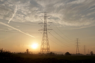 The silhouette of a high power electricity poles at sunrise in the morning