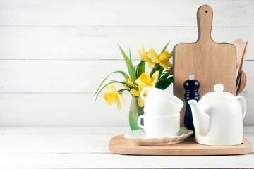 Obraz na płótnie Canvas Kitchen wide banner concept. Kitchen background for mockup with spoon, teapot, cups, bowls, flowers on wooden table .