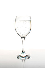 Glass of wine filled with sparkling water with reflection on a white background