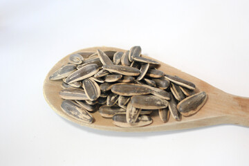 Sunflower seeds in wooden spoon over white background