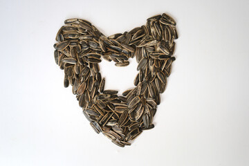 Pile of fried sunflower seeds with heart or love shape isolated on white background.