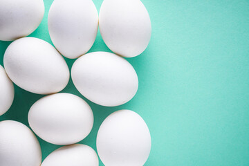 white chicken eggs on green pastel background