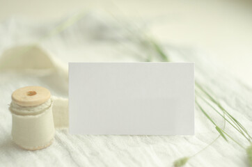 Summer stationery mockup scene with herbs, vintage spool of cotton braid, on a light background. Mockup card for greeting card or wedding invitation in minimal style.