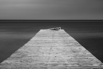 Obraz premium fine art photo of old wooden pier in smooth water with copy space