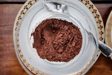 Overhead view of cinnamon powder, cocoa powder and cream in bowls on wooden table