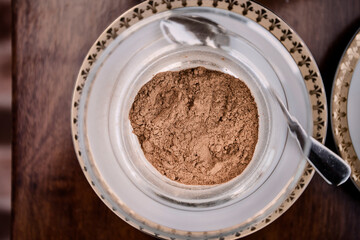 Overhead view of cinnamon powder, cocoa powder and cream in bowls on wooden table