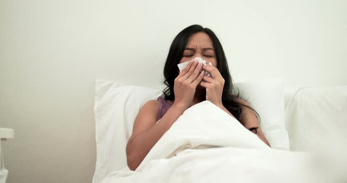 Asian woman  sneeze and has sick, Thai girl has cold and illness and lay down on bed in bedroom
