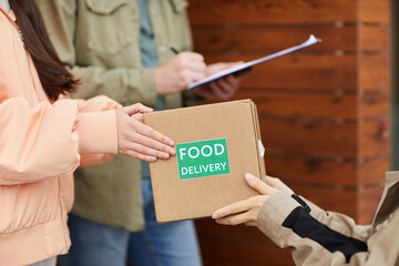 Close-up of courier delivering takeaway food to people while they standing outdoors