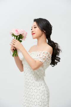 Young attractive Asian model like a bride with bridal bouquet at studio looking