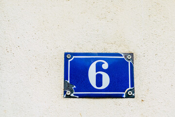 Plaque de rue avec numéro six - Signe sur le mur d'une maison