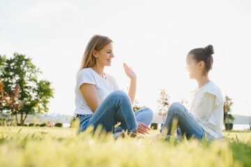 Naklejka na ściany i meble Mother and daughter having fun in the park. Happy family concept. Beauty nature scene with family outdoor lifestyle. Happy family resting together. Happiness and harmony in family life.