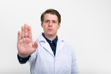 Portrait of young handsome man doctor showing stop gesture