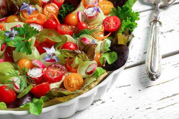 Low-calorie cold pie with fresh vegetables and soft cheese in a bowl and silver spatula on a white wooden background close-up