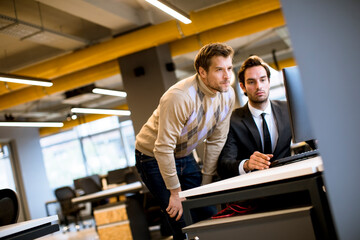 Two young businessmen discussing in office by the table