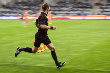Sideline referee running during football match - intentional blurry.