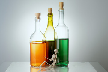 the skeleton lies on the background of three bottles with different liquids