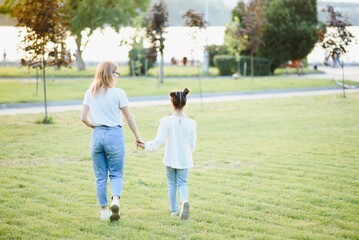 Naklejka na ściany i meble Mother and daughter having fun in the park. Happy family concept. Beauty nature scene with family outdoor lifestyle. Happy family resting together. Happiness and harmony in family life.