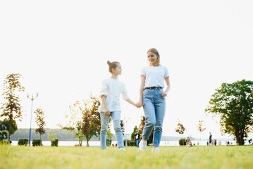 Mother and daughter having fun in the park. Happy family concept. Beauty nature scene with family outdoor lifestyle. Happy family resting together. Happiness and harmony in family life.
