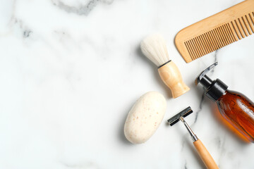 Shaving accessories for man on marble table. Flat lay composition with handmade soap, razor, shaving brush, bottle with foam gel, wooden hair comb.
