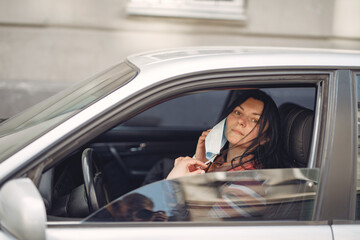 Woman in the city. Person in a mask. Coronavirus theme. Woman in the car.