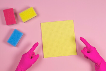 Woman hands with rubber gloves points up to sponges over pink background