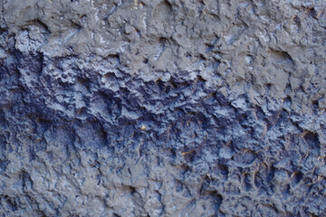 Blurred abstract background. Rough gray with a blue stripe surface of the cement wall. Old painted wall with cracks. Horizontal, close-up, free space. Construction and design concept.