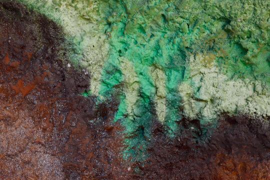 Blurred abstract background. Rough brown surface of a cement wall with green streaks of paint. Old painted wall with cracks. Horizontal, close-up, free space. Concept of construction and design. © Nataliia