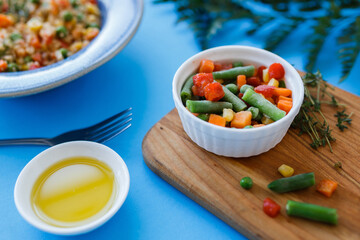 pilaf in a blue plate on a blue background. frozen vegetables