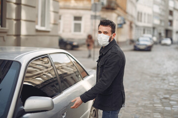 Fototapeta na wymiar Man in a city. Person in a mask. Coronavirus theme. Man by the car.