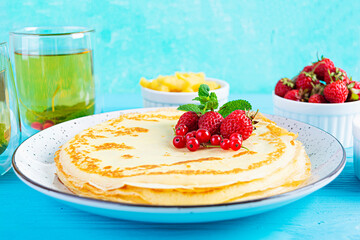 Pancakes with caramelized apples, raspberries, strawberries and red currants. Brunch with green tea and crepes.