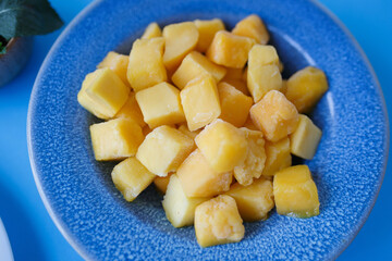 cubes of frozen pineapple in a blue plate close-up