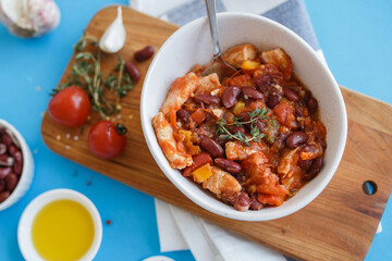 vegetable stew in a white plate on a wooden board close-up. blue background